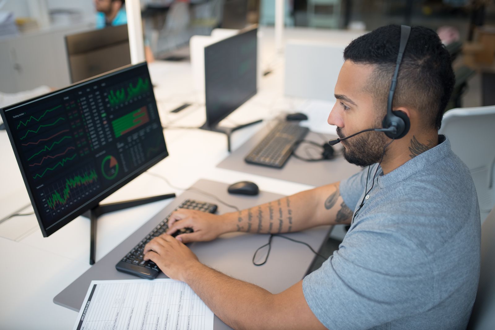 Security analyst reviewing dashboards at a workstation with an assessment form on the desk