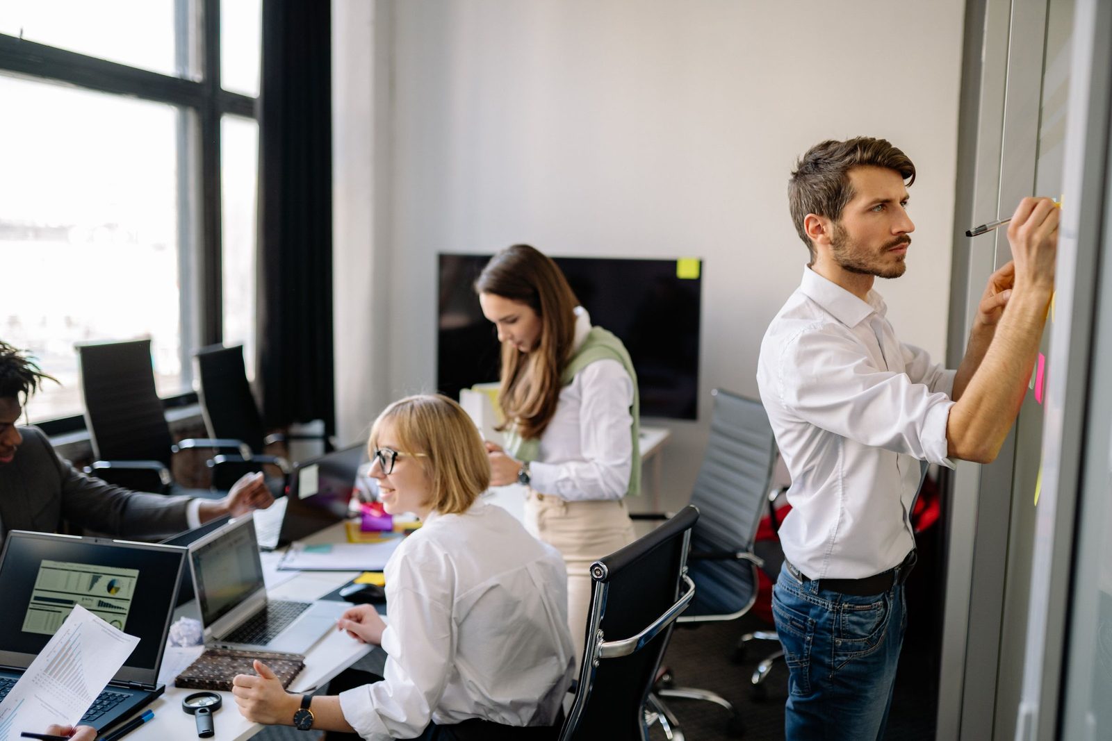 A diverse team of colleagues collaborating around a laptop in a modern office
